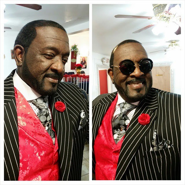 Apostle Johnny L. Kemp Sr. in a pinstripe suit with a red vest and red rose boutonniere